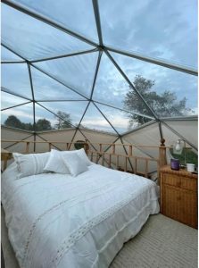 اتاق خواب به سبک زیر شیروانی دارای یک تخت کویین و سقف شیشه‌ای